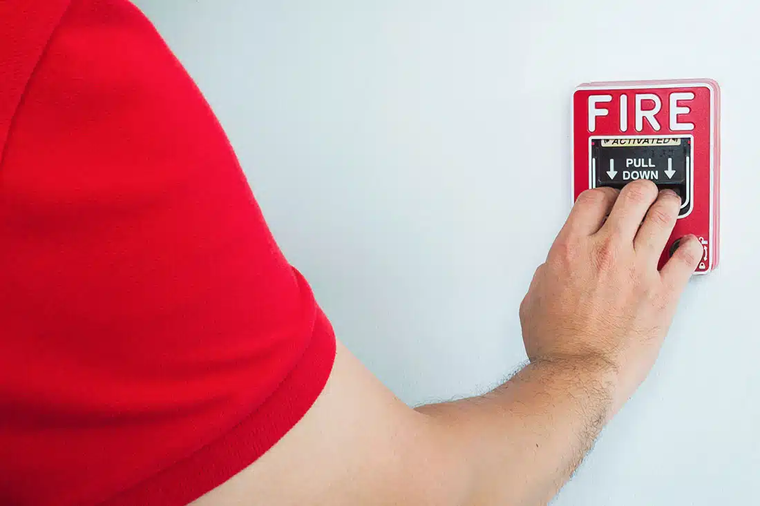 A person pulling a fire alarm setting off an evacuation