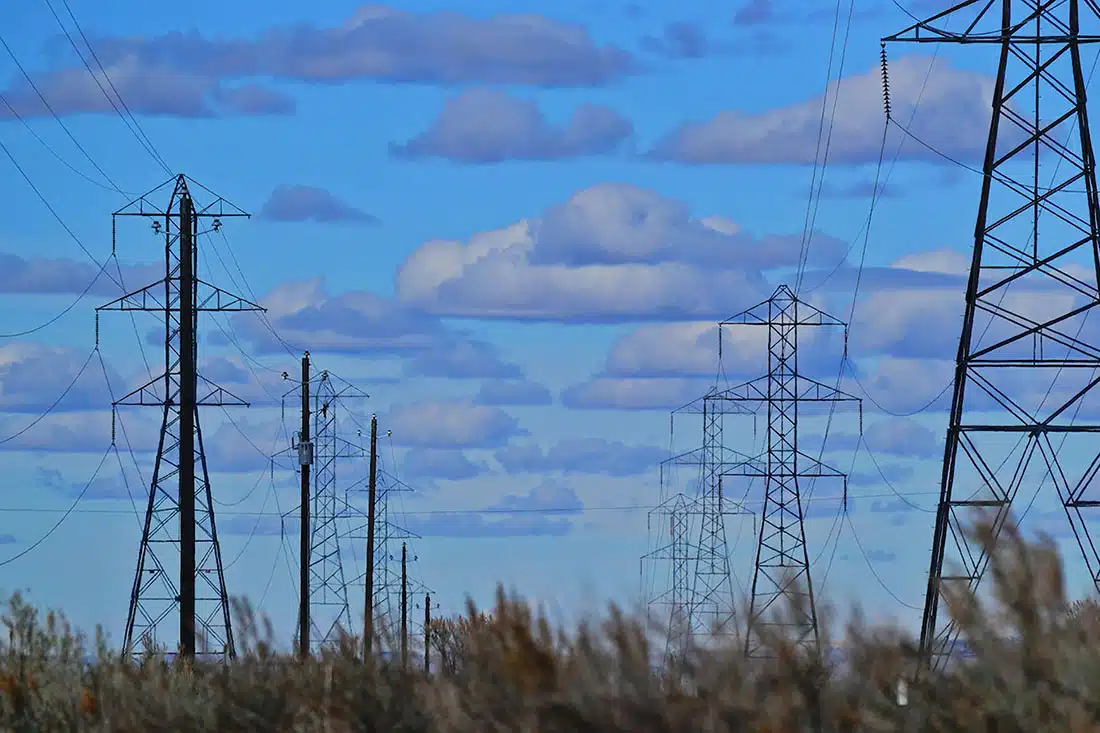 A blue skyline with a series of powerlines fading into the distance.