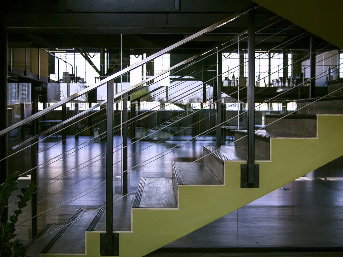 A close up of the bottom set of steps with yellow sides. There’s an industrial-style office in the background