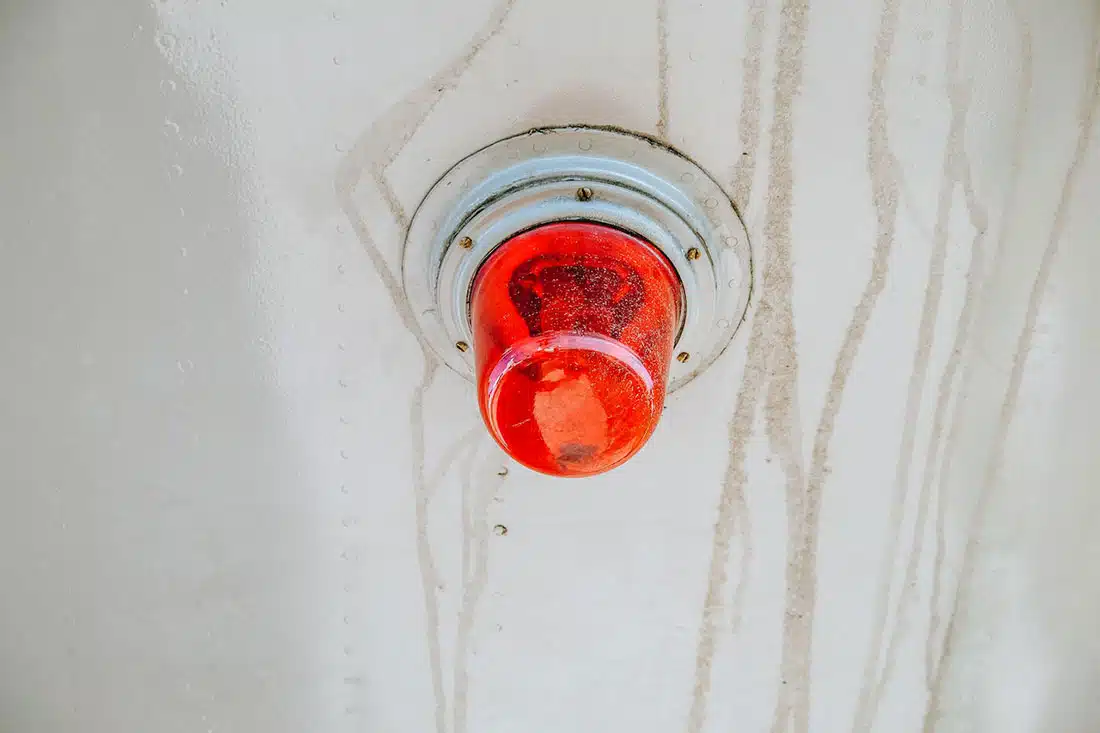 A close up of a red emergency beacon light on light coloured ceiling