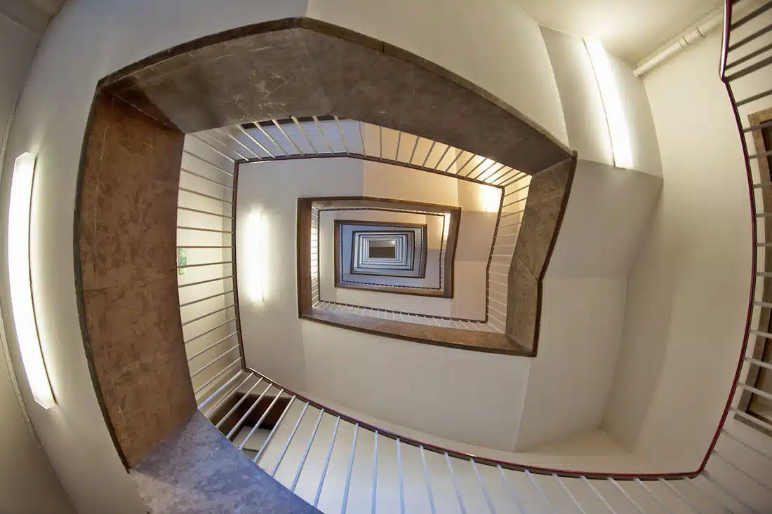 An upwards shot of a long spiralling brown and white staircase