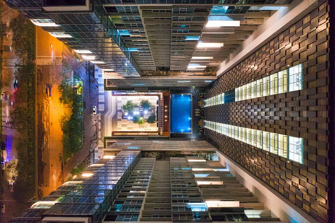 Looking to the ground from the top of a skyrise building at a pool and road below